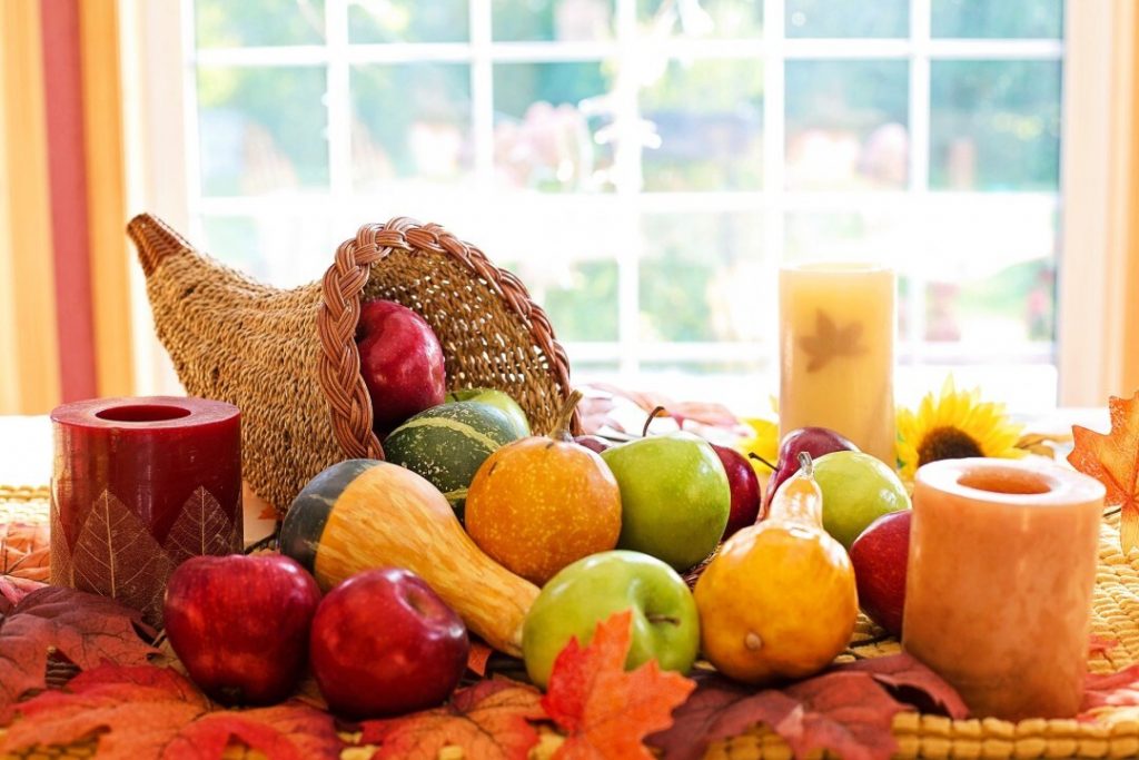 horn of plenty sitting on a table with squash apples pears pouring out of it